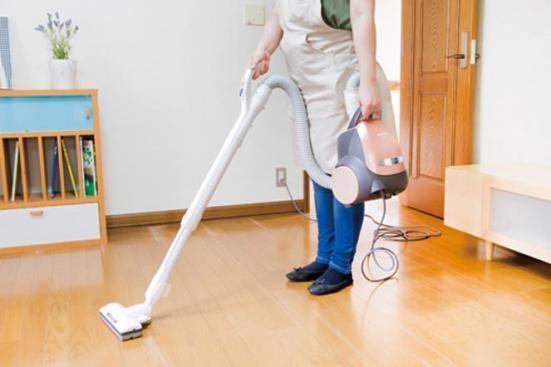 掃除機で床を掃除する女性の画像