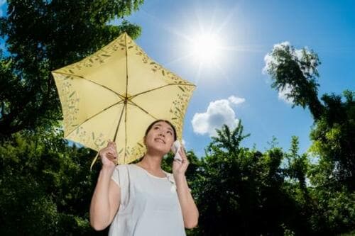 夏の日差しで暑そうにする女性のイメージ画像