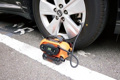 車のタイヤに電動式空気入れで空気を入れている様子