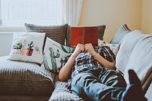 ソファで寝転がって本を読む人