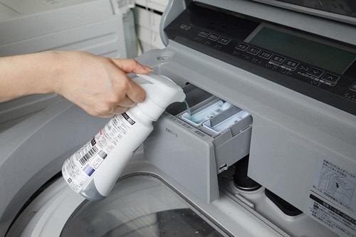 洗濯機に洗剤を投入している