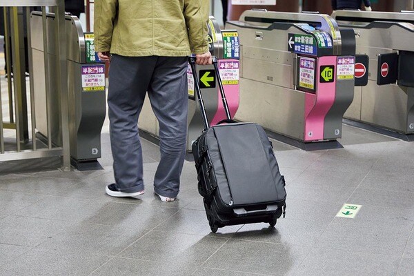 駅の改札前でキュリーバッグを持つ男性の画像