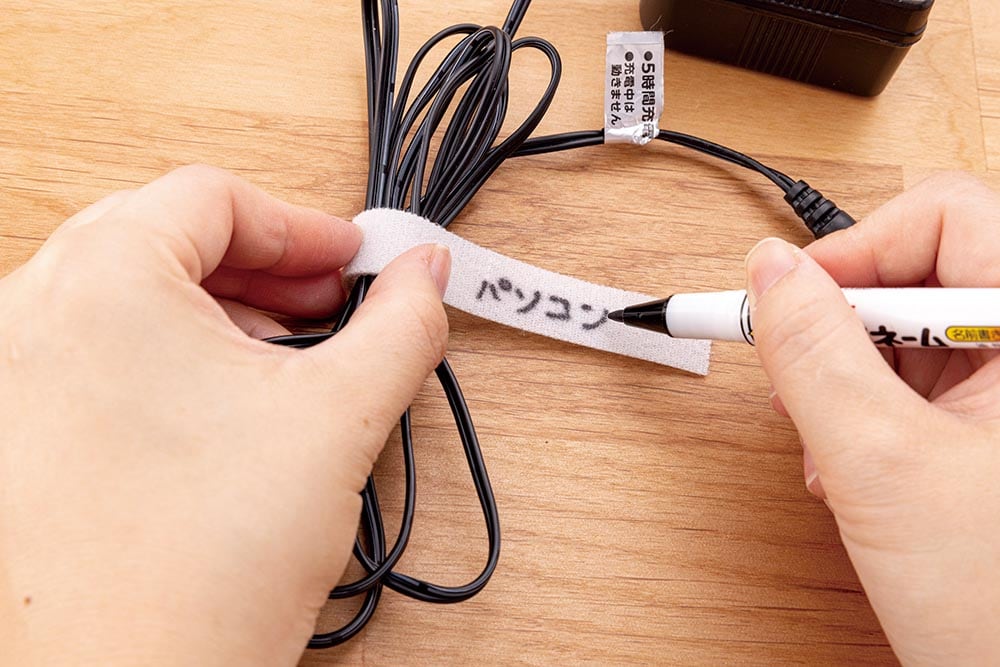 無印良品 ミシン目入り結束テープをコードに巻いて名称を書いている様子